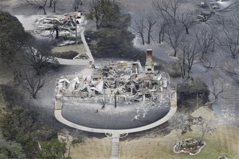 This aerial photograph shows a large home is left in ashes  on Possum Kingdom Lake, Texas on Wednesday April 20, 2011.   Federal firefighters and officials from several U.S. agencies joined the fight against a massive wildfire burning 70 miles west of Fort Worth on Wednesday, the same day a Texas firefighter died from injuries suffered while battling a blaze earlier this month.  The fire at Possum Kingdom Lake is among several that have scorched about 1 million acres across bone-dry Texas in the past two weeks. (AP Photo/Star-Telegram, Ron T. Ennis)